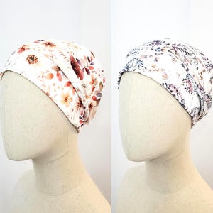 Può includere: Due fasce per capelli bianche con stampa floreale, una con fiori arancioni e marroni e l'altra con fiori grigi e viola. Le fasce sono su manichini con pelle bianca.