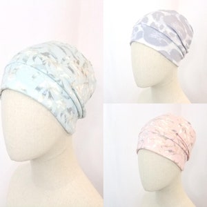 May include: Three different patterned knit beanies. The beanies are light blue with a silver pattern, gray with a white pattern, and pink with a silver pattern.