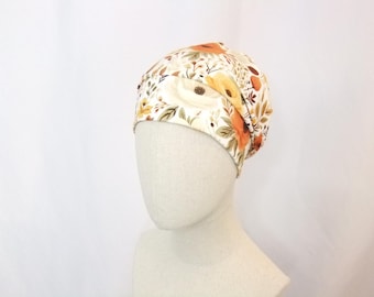 May include: A white floral print beanie with orange and yellow flowers. The beanie is made of soft, stretchy fabric and is perfect for keeping your head warm and stylish.