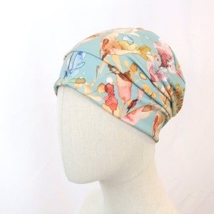 May include: A light blue beanie with a floral print featuring watercolor-style flowers in shades of pink, orange, and yellow.
