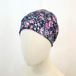 Könnte beinhalten: Ein marineblauer Turban mit einem rosa-weißen Blumenmuster. Der Turban ist aus einem weichen, dehnbaren Stoff gefertigt und eignet sich perfekt für verschiedene Anlässe.