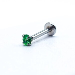 May include: A silver body piercing with a small green gem. The piercing is made of surgical steel and is suitable for a variety of body piercings.