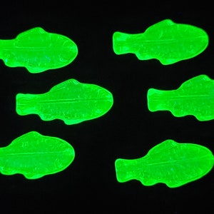 May include: Six green glass fish shaped candy decorations. The candy is translucent and has a slightly textured surface.