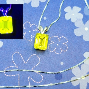 Puede incluir: Un collar de cadena de plata con un colgante de piedra preciosa de corte esmeralda amarillo. El colgante está engastado en un engaste de bisel de plata.