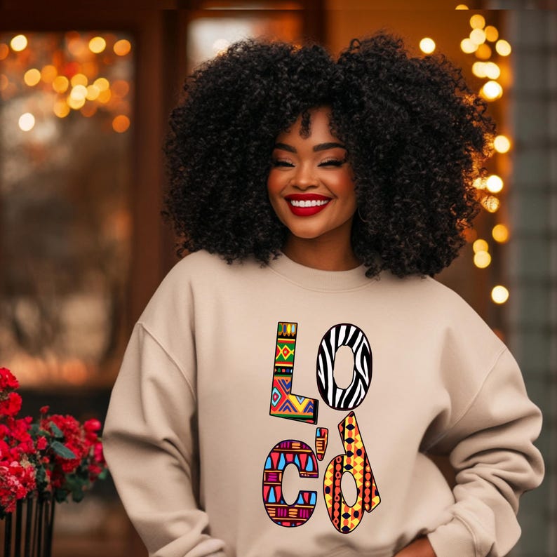 Puede incluir: Una sudadera beige con la palabra "Loc'd" impresa en la parte delantera en letras con patrones coloridos. Las letras est&aacute;n formadas por diferentes patrones geom&eacute;tricos e estampados de animales, incluidas rayas de cebra.