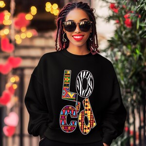 Puede incluir: Sudadera negra con la palabra "LOc'd" impresa en letras coloridas y estampadas. Las letras est&aacute;n decoradas con dise&ntilde;os geom&eacute;tricos y de estampado animal.