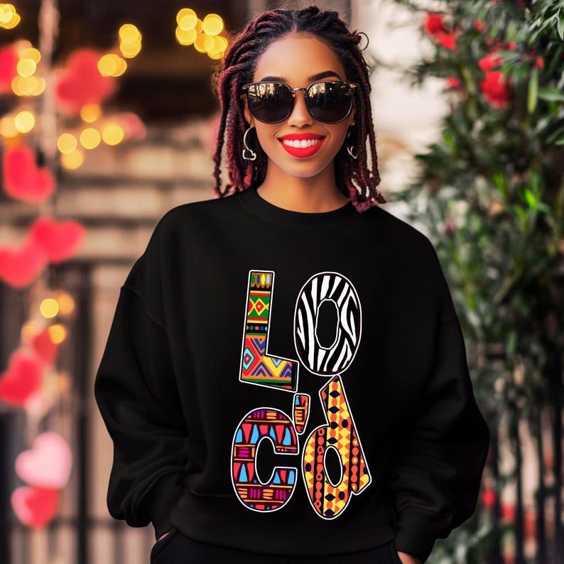Puede incluir: Sudadera negra con la palabra "LOc'd" impresa en letras coloridas y estampadas. Las letras est&aacute;n decoradas con dise&ntilde;os geom&eacute;tricos y de estampado animal.