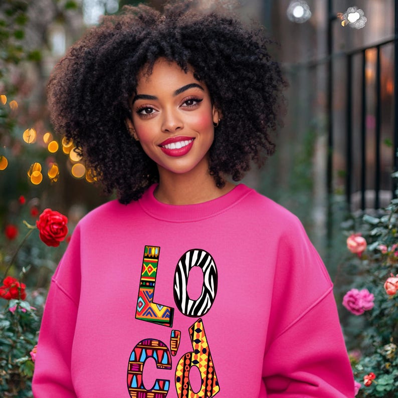 Puede incluir: Una sudadera rosa con la palabra "LOCAL" impresa en la parte delantera en letras coloridas y estampadas. Las letras est&aacute;n formadas por diferentes formas geom&eacute;tricas e estampados de animales.