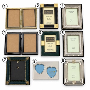 May include: A collection of nine picture frames including gold, black, green, and silver finishes. Some frames are hinged doubles, others are single rectangular or heart-shaped designs. Several feature St. Andrew Collection or Godinger Silver labels.