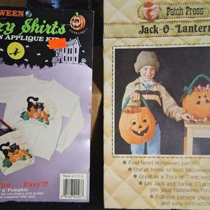 May include: Two Halloween craft kits: a Glitzy Shirts iron-on applique kit featuring a black cat and pumpkin design on a white sweatshirt, and a Patch Press Jack-O-Lantern pattern kit for creating a fabric pumpkin-shaped treat bag.