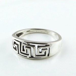 May include: A silver ring with a Greek key design. The ring is made of sterling silver and has a polished finish.
