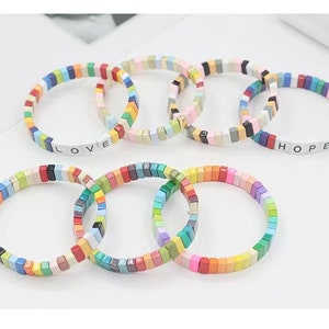 May include: A set of colourful tile bracelets with the words "LOVE" and "HOPE" spelled out on two of the bracelets.