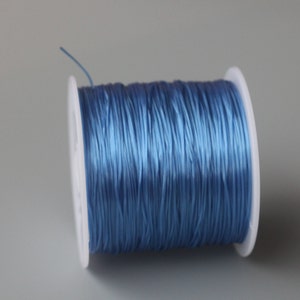 Peut inclure: Une bobine de cordon &eacute;lastique bleu clair, enroul&eacute;e autour d'une bobine en plastique blanc.