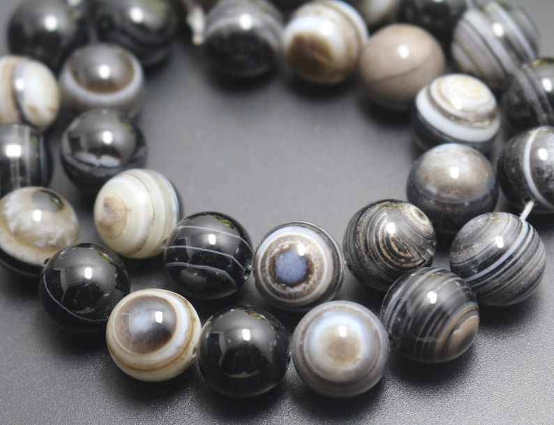 May include: A strand of black and white agate beads. The beads are round and have a polished finish. The agate has a swirling pattern of black and white lines.