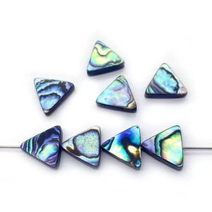 May include: A collection of iridescent triangle-shaped beads. The beads display a range of colors, including blues, greens, and purples, with a shimmering, pearlescent effect. The beads are strung on a thin, silver wire, suggesting they are for jewelry making.