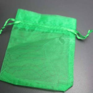 Puede incluir: Una bolsa de regalo de organza verde claro y transparente con cierre de cord&oacute;n. La bolsa est&aacute; hecha de una tela ligera y transl&uacute;cida, ideal para peque&ntilde;os regalos o favores.