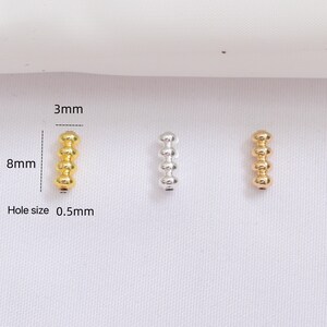 May include: Three small, cylindrical beads, each with four rounded segments. One is gold, one is silver, and one is gold. The gold beads are 8mm long, 3mm wide, and have a 0.5mm hole. These beads are suitable for jewelry making.