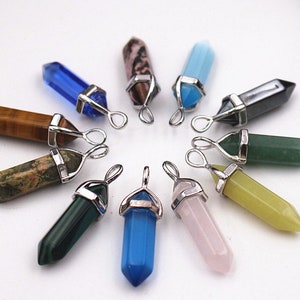 May include: Assortment of 12 crystal point pendants with silver-tone metal caps and loops. The crystals are in various colours, including blue, green, pink, brown, and black.