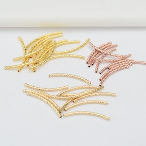 Puede incluir: Una colección de cuentas de metal dorado y dorado rosa. Las cuentas son pequeñas y tienen un diseño retorcido. Son perfectas para la elaboración de joyas.