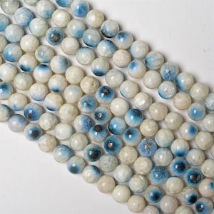Peut inclure: Un brin de perles d'agate blanches et bleues. Les perles sont rondes et ont un aspect marbré. Les perles sont enfilées sur un fil transparent.