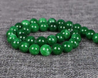 May include: A strand of round, green jade beads. The beads are smooth and polished, with a slight variation in colour.