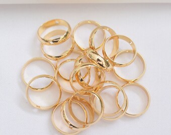 May include: A pile of gold-colored metal rings with a small hole in each ring. The rings are arranged in a random pattern.