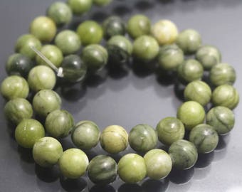 May include: A strand of green jade beads with a marbled pattern. The beads are round and smooth, and they are strung on a clear thread.