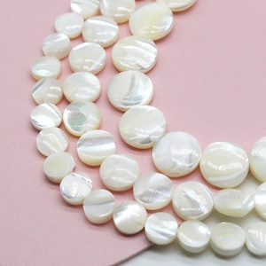 May include: A strand of white mother of pearl beads, each bead is round and flat, with a slightly iridescent sheen.