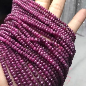 Könnte beinhalten: Eine Strähne aus tiefrosa Rubinperlen, jede Perle ist facettiert und hat eine leicht unregelmäßige Form. Die Perlen sind zu einer langen Halskette aufgereiht.