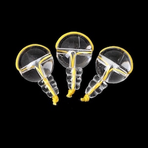 Peut inclure: Trois perles en verre transparent avec un cordon jaune enroulé autour du haut de chaque perle. Les perles ont une petite tige en verre transparent.