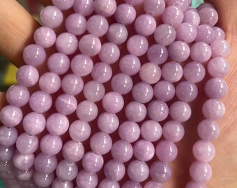 Puede incluir: Un collar de cuentas redondas de piedra preciosa de color lila claro. Las cuentas tienen una superficie lisa y pulida y un brillo sutil. Las cuentas están ensartadas, creando un collar o una pulsera. Las cuentas tienen aproximadamente 8 mm de diámetro.