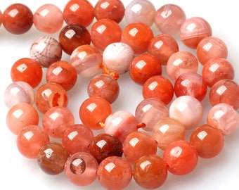 May include: A strand of round, translucent agate beads in shades of orange, pink, and white. The beads have a natural, polished finish and are strung on a thin, red thread.