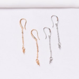 May include: Two pairs of dangle earrings with a chain and a small bead at the end. One pair is gold and the other is silver.