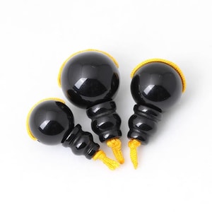 May include: Three black obsidian prayer beads with gold trim and tassels. The beads are of different sizes and are arranged in a semi-circle.