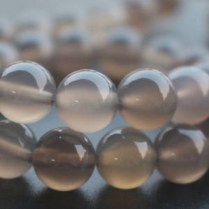 May include: A strand of grey gemstone beads. The beads are round and smooth, with a slightly translucent appearance.