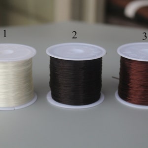 May include: Three spools of elastic cord, one white, one black, and one brown. The spools are labeled 1, 2, and 3.