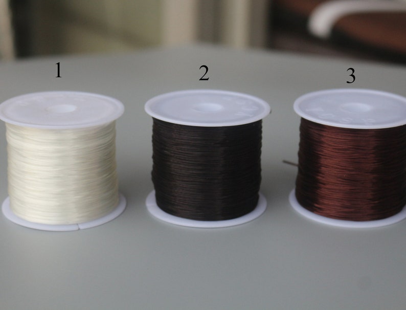 May include: Three spools of elastic cord, one white, one black, and one brown. The spools are labeled 1, 2, and 3.