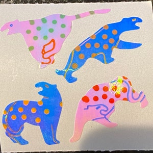 May include: Four colorful stickers featuring stylized animal designs. The stickers include a pink cheetah with green polka dots, a blue cheetah with orange polka dots, a blue animal with orange polka dots, and a pink animal with red polka dots.