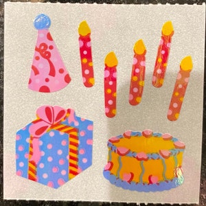 May include: A collection of colorful birthday-themed stickers. Includes a pink party hat, red candles with yellow flames, a blue gift box with a pink bow, and a yellow cake with blue and pink frosting.