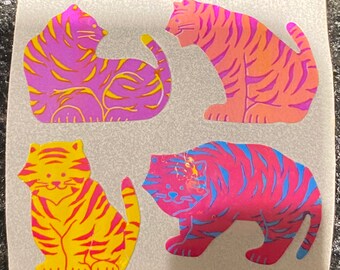 May include: Four colorful tiger stickers. Each sticker features a different pose and color scheme, including pink and yellow, orange and pink, purple and yellow, and pink and blue. The stickers are on a white background.