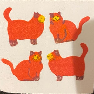 May include: Four orange cat stickers with yellow faces and brown accents are arranged on a white square. The cats have their tails up and are in various poses. The stickers have a textured appearance.