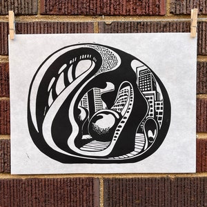 May include: Black and white linocut print of a cityscape with a large, round, abstract shape in the center. The print is on white paper.