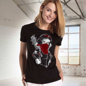 May include: Black t-shirt featuring a graphic of Snow White with a red bandana, holding a guitar. The design includes skull accents and a red bow. The shirt is a crew neck style.
