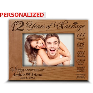 May include: Personalized wooden picture frame with a couple in the photo. The frame is engraved with "12 Years of Marriage" and "Happy Anniversary Amber & Adam April 6, 20XX". The frame also has a list of time measurements, such as "144 months of love", "626 weeks of joy", and "4384 days of loyalty".