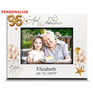 May include: White picture frame with a photo of a woman and a child. The frame has gold balloon-shaped "96" and the words "And Fabulous". The bottom of the frame says "Happy Birthday" and "Elizabeth 20/15/20XX".