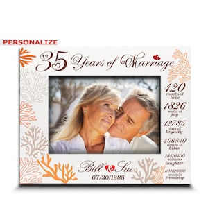May include: White picture frame with a photo of a couple, celebrating 35 years of marriage. The frame has coral-like designs in orange and brown, with text that reads "35 Years of Marriage," and "Bill & Sue 07/30/1988."