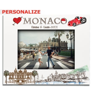 May include: A white photo frame with a red heart and the words "I love Monaco" in black text. The frame has a photo of a couple walking hand-in-hand across a street in Monaco. The frame also has a red race car illustration and the text "Emma & Liam - 20XX".