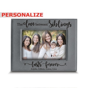 May include: Gray leather picture frame with a photo of four women and a baby. The frame has the text "The love between siblings lasts forever" and the names "Linda, Lilian, Luna, Lisa".