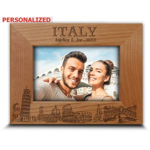 May include: Personalized wooden photo frame with a couple's photo in front of an Italian landmark. The frame is engraved with the text "ITALY" and "Anjelica & Joe - 20XX" and features a detailed illustration of iconic Italian landmarks.