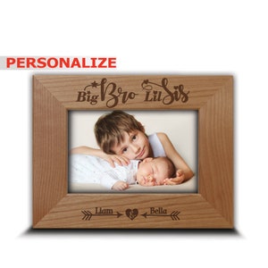 May include: Personalized wooden photo frame with the text "Big Bro Lil Sis" and arrows pointing to the names "Liam" and "Bella". The frame features a photo of a young boy and a baby girl.